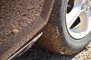 Mud-Covered Tire on Gravel Surface
