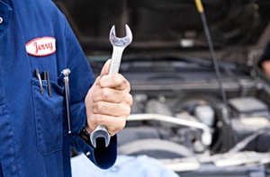 Mechanic in a blue uniform holding a wrench