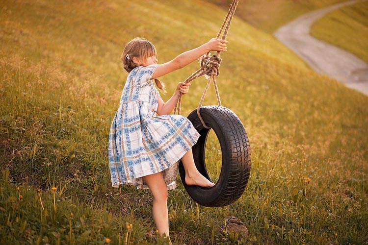 A young girl joyfully swings on a tire swing A young girl joyfully swings on a tire swing