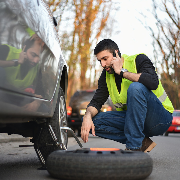 Man fixing car tire on the side of road