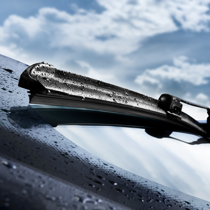 Closeup of wet windshield wiper, wipping windscreen outside