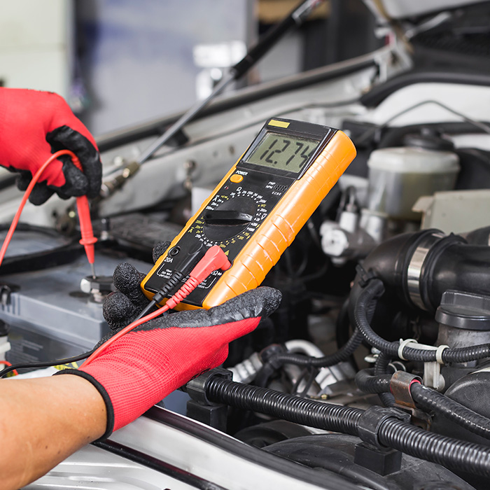 A technician is checking the car battery for availability