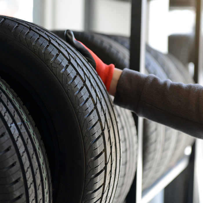 Male mechanic holding tire while repairing service garage background