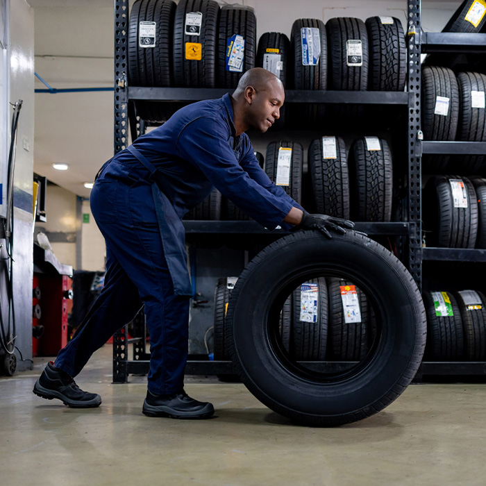Mechanic changing a flat tire and carrying a wheel at a repair garage