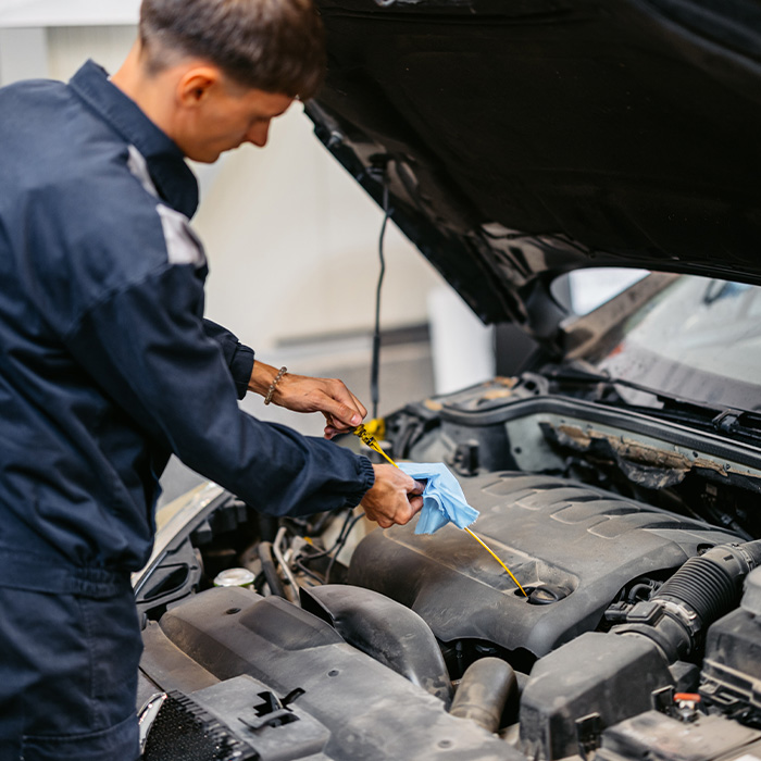car mechanic checking an engine oil on a car he is working on in his garage