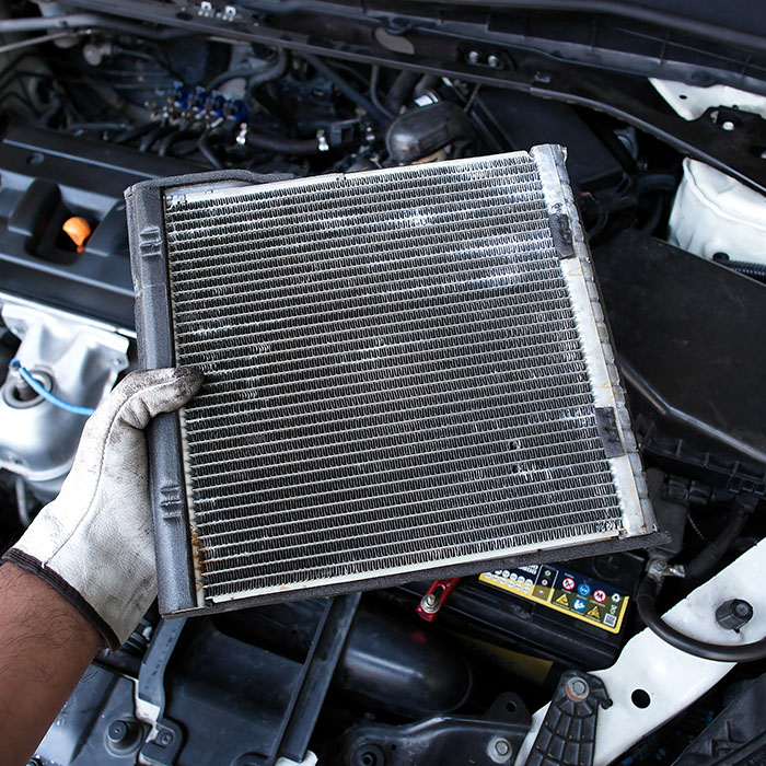 Mechanic holding radiator or evaporator of car air conditioner during car maintenance
