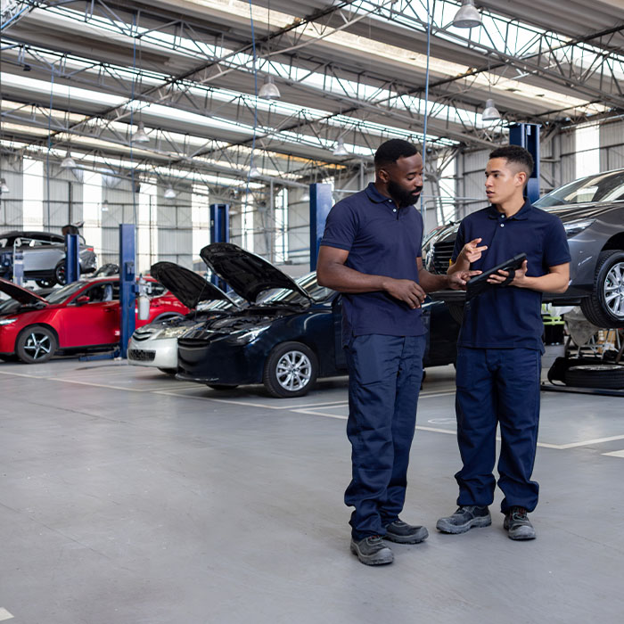Mechanics discussing the diagnosis of a car at an auto repair shop