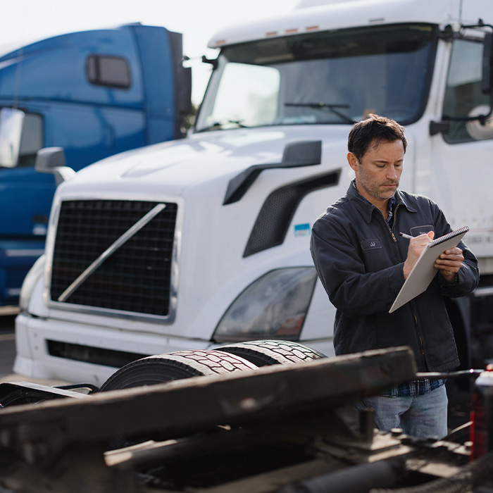Truck driver inspecting a semi-truck trailer in a parking lot