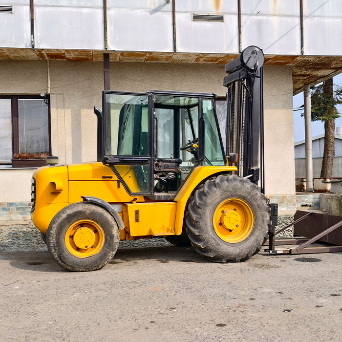Yellow forklift stands idle outside factory.