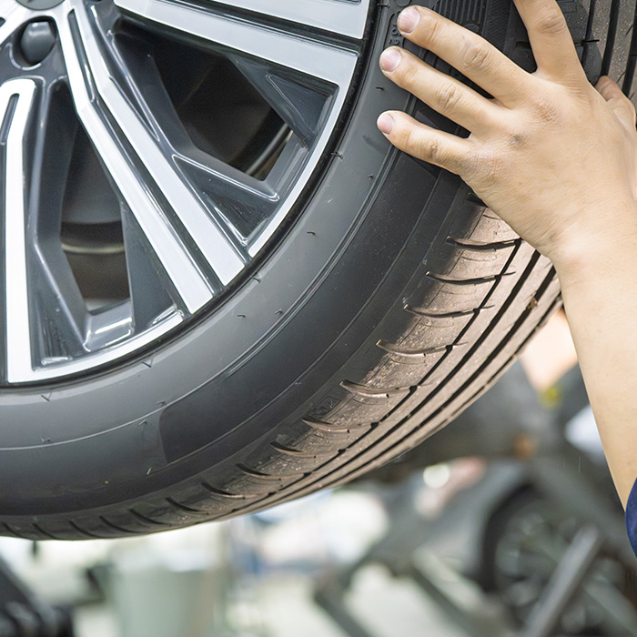Mechanic inspecting car tire tread wear