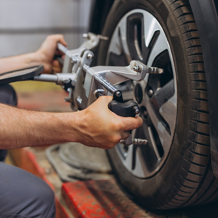 Car mechanic doing tire alignment and suspension check on a car wheel