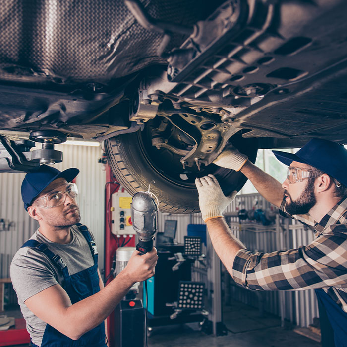 Professionals in blue overalls, protective spectacles are examining changing tires